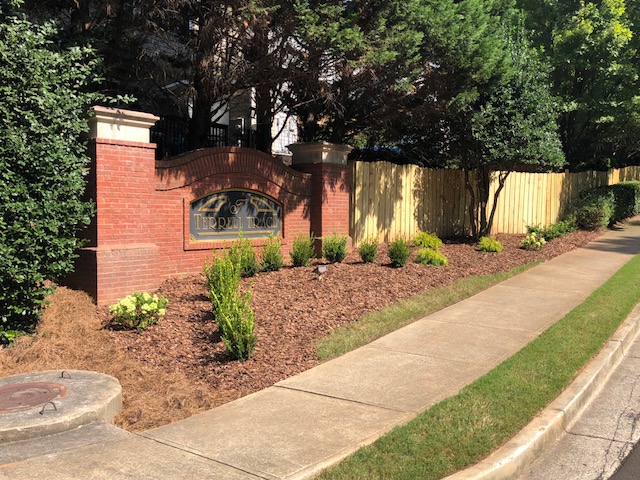 Professionally maintained landscape in front of a fence.